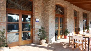 A stone building with large arched windows and a wooden door. There are potted plants and outdoor seating. - Hotel Molí de la Torre (Bigues I Riells)