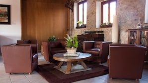 A cozy living room with leather sofas, a wooden coffee table, and a stone wall. - Hotel Molí de la Torre (Bigues I Riells)