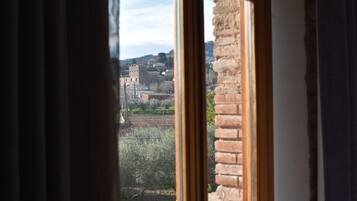 Vista desde una ventana a un paisaje rural con un edificio de piedra y árboles.