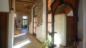 A hallway with stone walls, wooden beams, and a large mirror. - Hotel Molí de la Torre (Bigues I Riells)