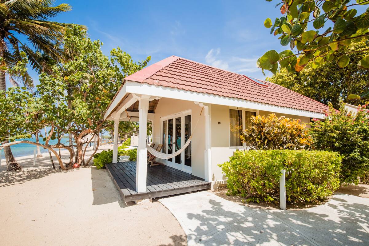 A beachfront property with a covered porch, a hammock, and a view of the ocean.