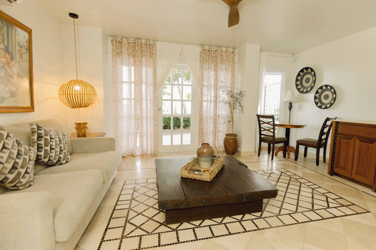 A living room with a sofa, coffee table, and dining area with chairs.