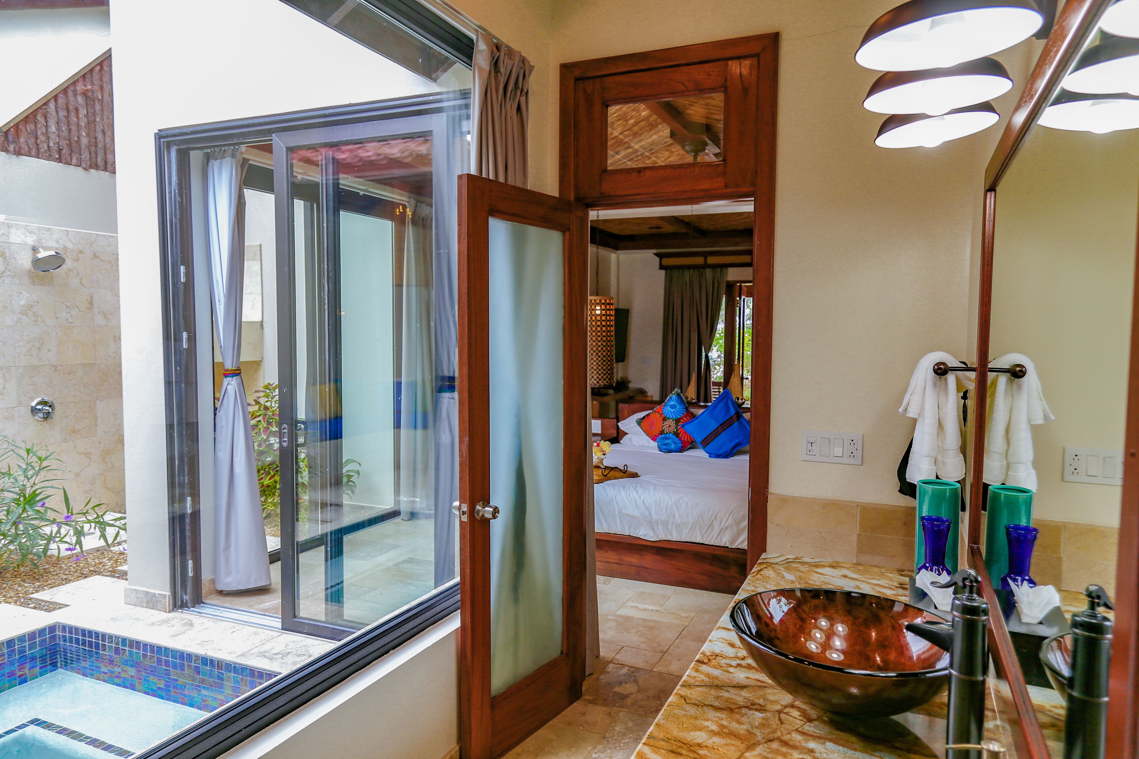 A bathroom with a large mirror, a bowl sink, and a shower area.