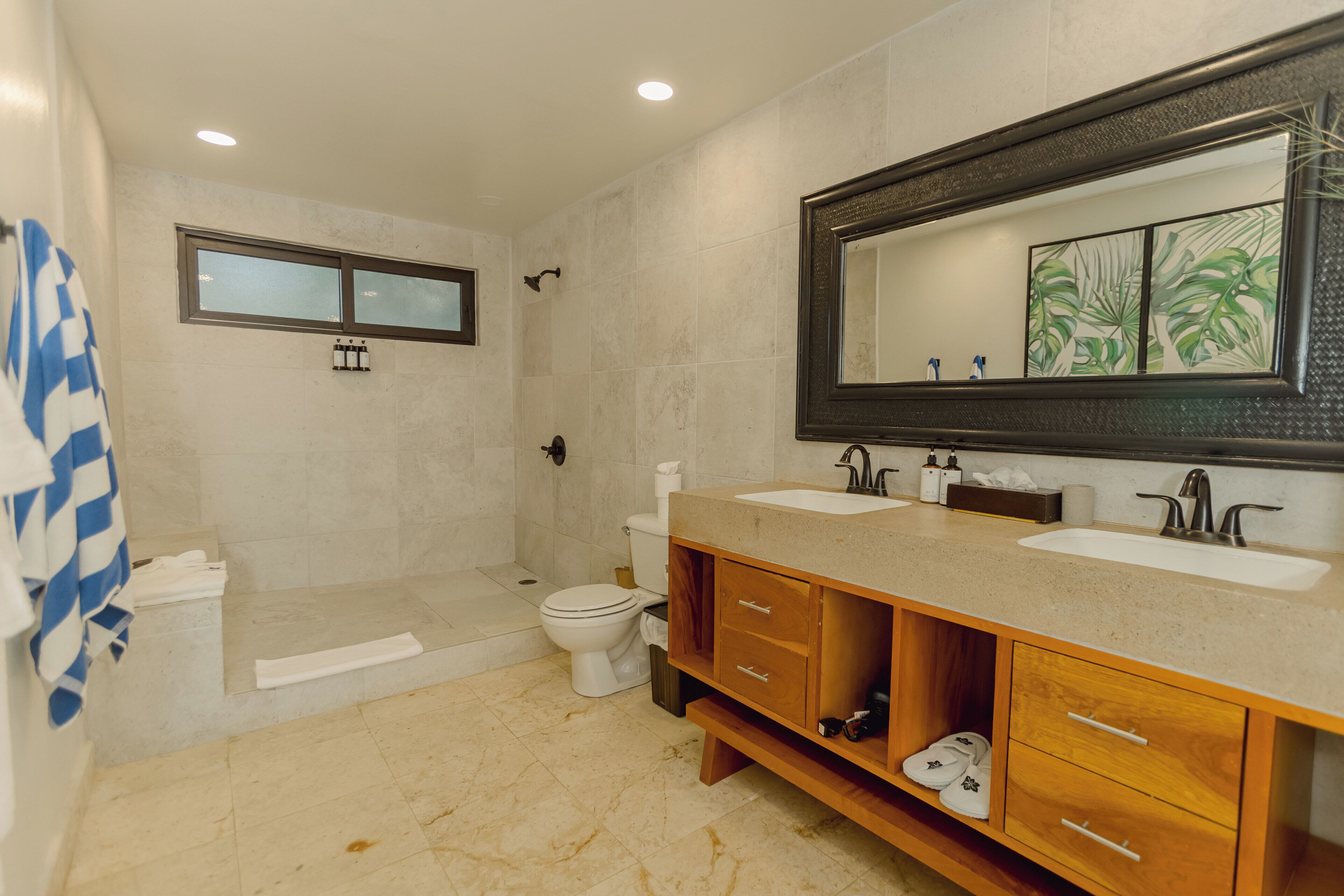A modern bathroom with a walk-in shower, two sinks, and a large mirror.