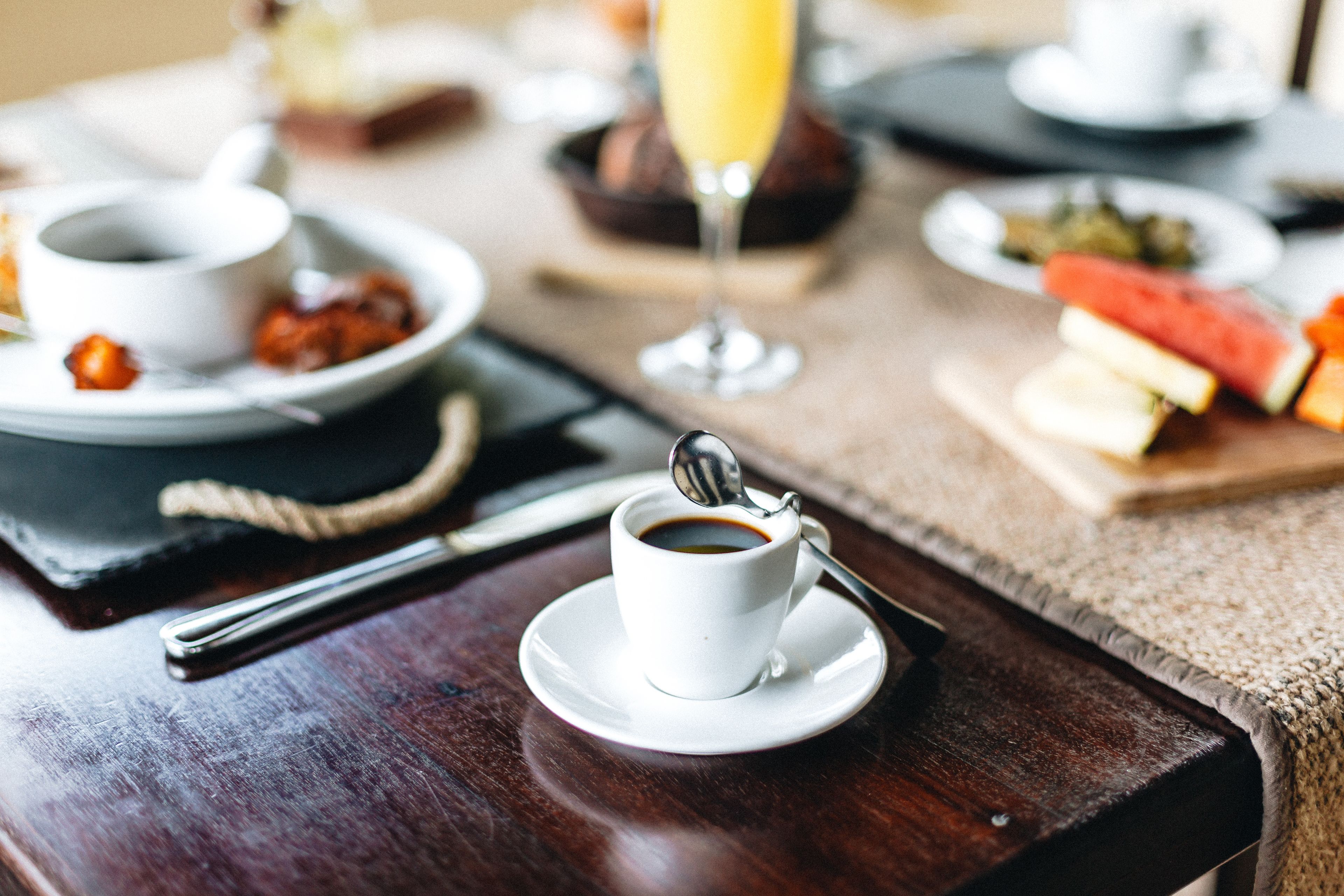 A breakfast setting with a cup of coffee, a glass of orange juice, and various breakfast items on plates.