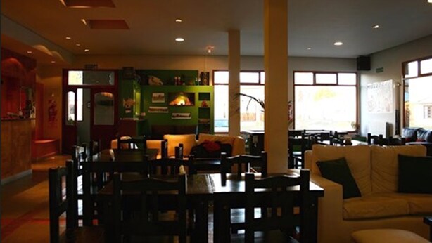 A spacious living area with a dining table and chairs, a sofa, and a fireplace. - Hotel Punta Norte (El Calafate)