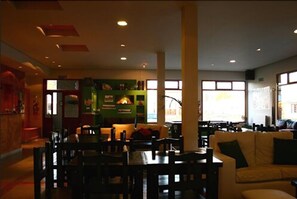 A spacious living area with a dining table and chairs, a sofa, and a fireplace. - Hotel Punta Norte (El Calafate)