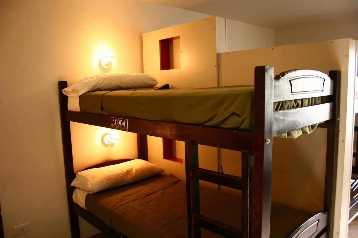 A bunk bed room with a light fixture above the bed and a small window.