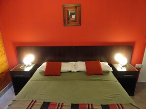 A hotel room with a large bed, two bedside tables with lamps, a red wall, and a framed picture above the bed. - Hotel Punta Norte (El Calafate)