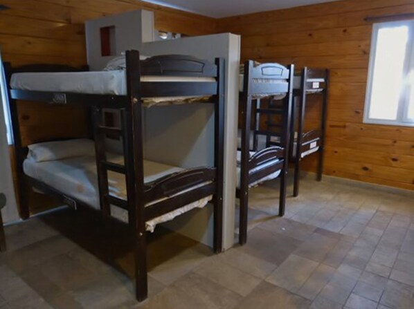 A bunk bed room with wooden walls and a tiled floor.