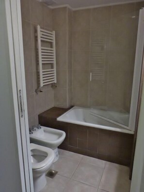 A bathroom with a bathtub, two bidets, and a toilet. - Hotel Punta Norte (El Calafate)