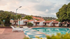 A pool area with lounge chairs, a tiled deck, and a view of terraced houses in the background. - Hotel Faranda Bolivar Cucuta, a member of Radisson Individuals (San José de Cúcuta)