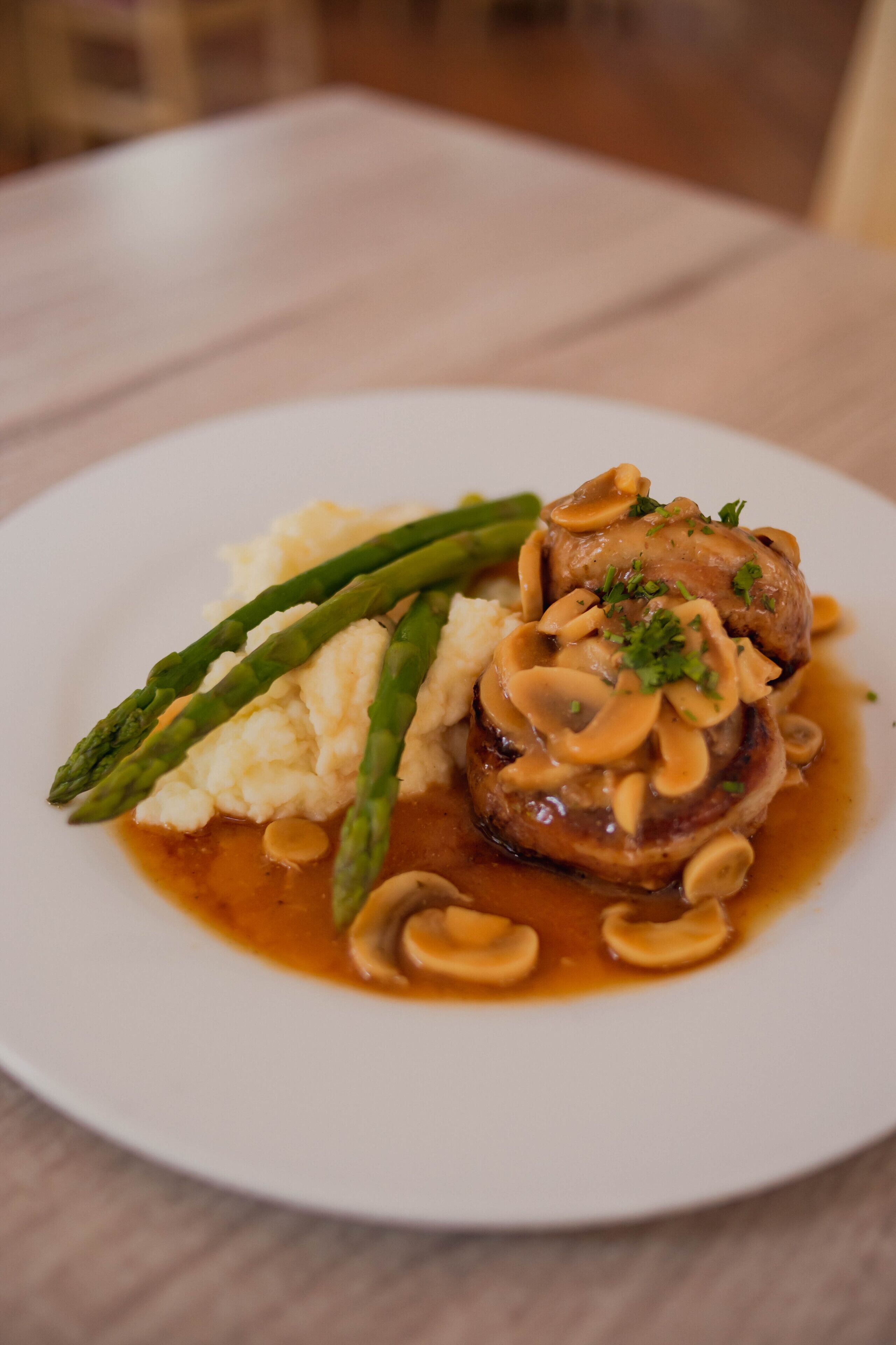 A plate with a meat dish, mashed potatoes, and asparagus.