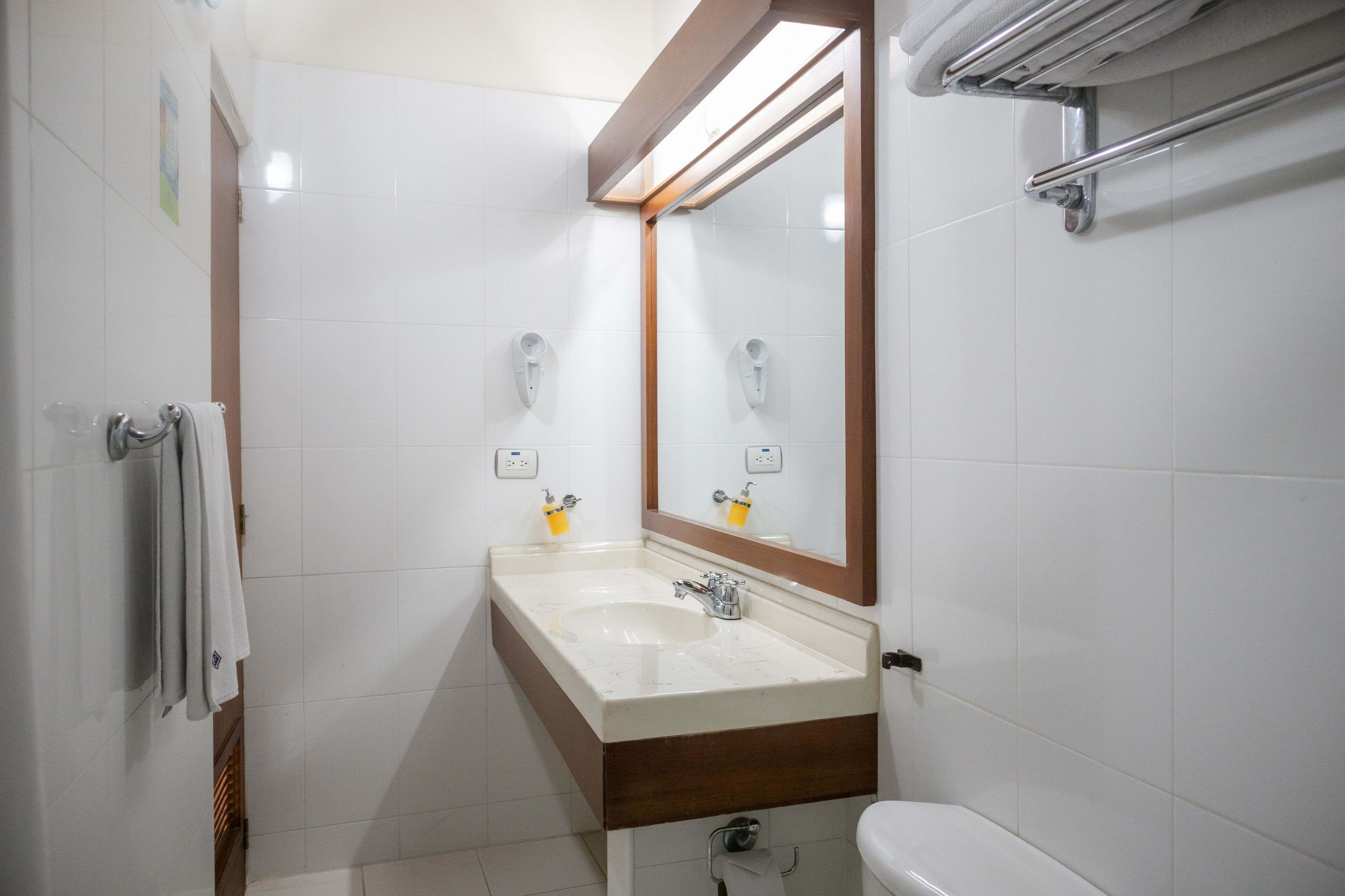 Un baño con un lavamanos blanco, un espejo y un inodoro.