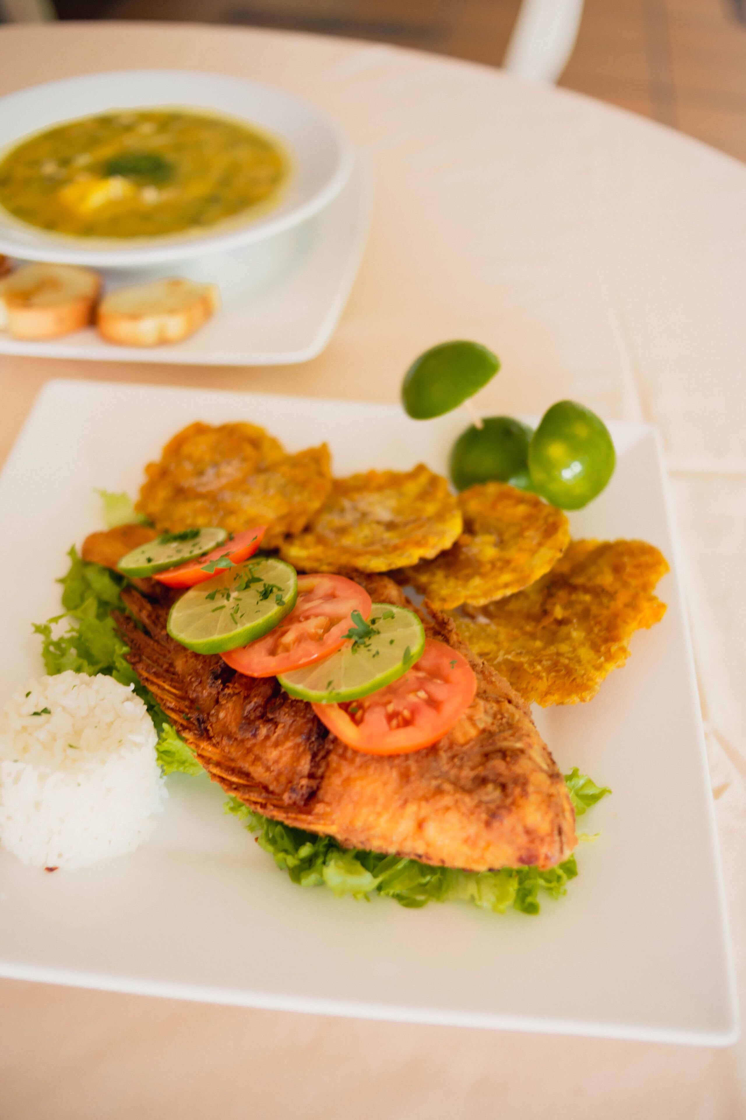 Une assiette contenant un filet de poisson, du riz et des bananes plantains frites.