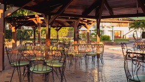 An outdoor patio area with multiple tables and chairs, a covered roof structure, and a view of a building in the background. - Hotel Faranda Bolivar Cucuta, a member of Radisson Individuals (San José de Cúcuta)
