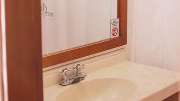 Un baño con un espejo de marco de madera, un lavamanos y una cortina de ducha.