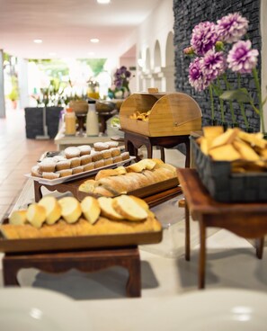 A buffet setup with various baked goods and pastries on display.