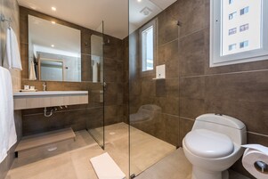 A modern bathroom with a glass shower enclosure, a toilet, and a sink with a mirror above it.