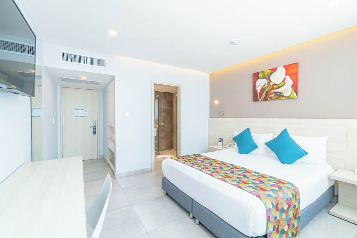 Una habitación de hotel moderna con una cama grande, un escritorio y una zona de ducha.