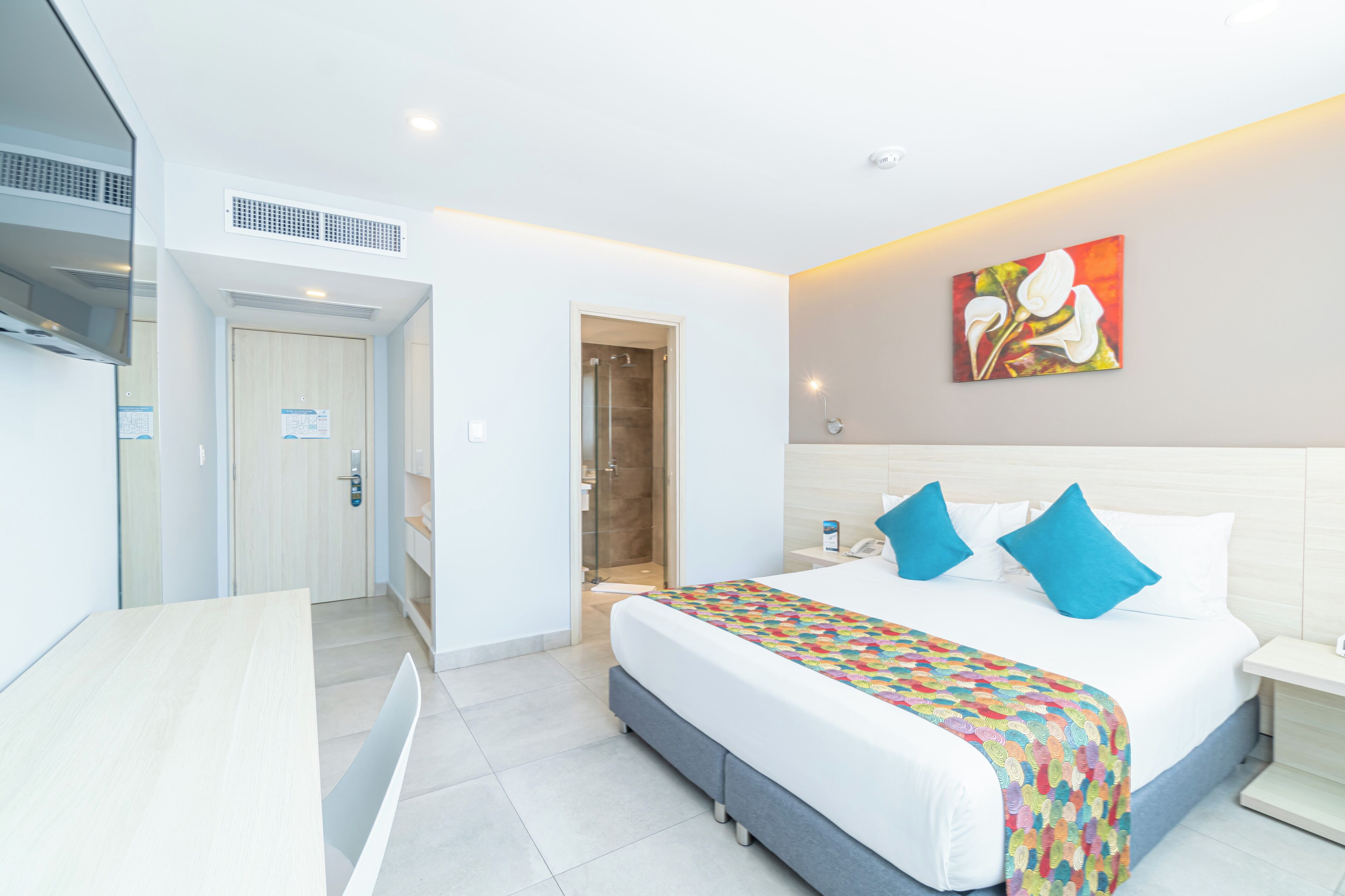 A modern hotel room with a bed, bedside table, and a shower area.
