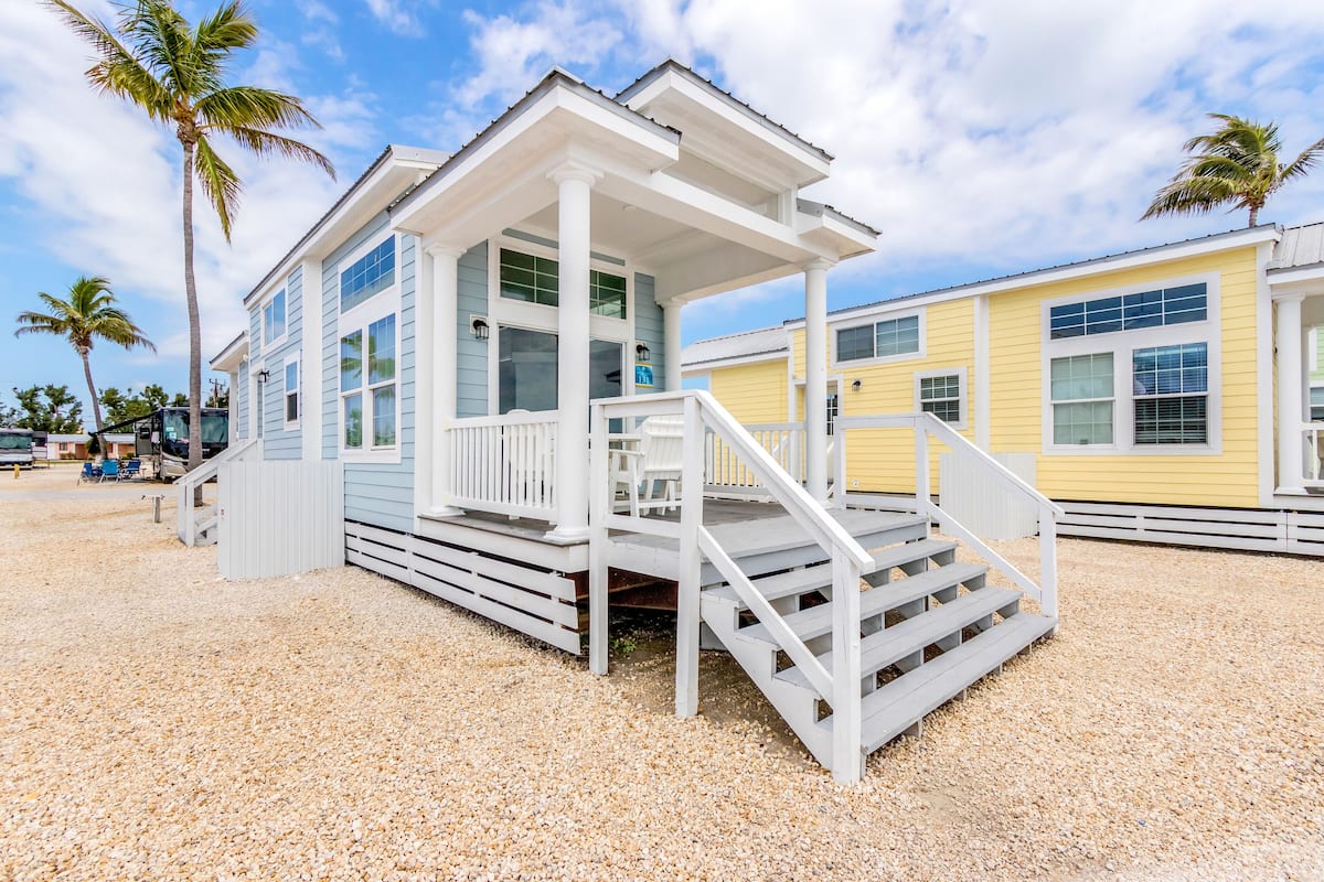 A beachfront house with a covered porch and steps leading to the entrance.