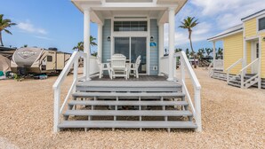 Uma propriedade à beira-mar com um deck coberto, área de estar externa e uma van motorizada visível.
