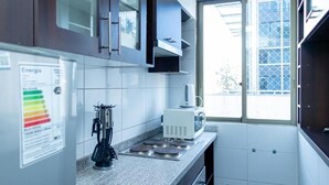 Een moderne keuken met witte tegels, een koffiezetapparaat en een fornuis.