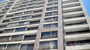 Een hoog gebouw met meerdere balkons en een heldere lucht.