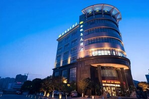 A multi-story hotel with a curved facade, large windows, and a prominent entrance. - Treasure Island Hotel (Wenzhou)