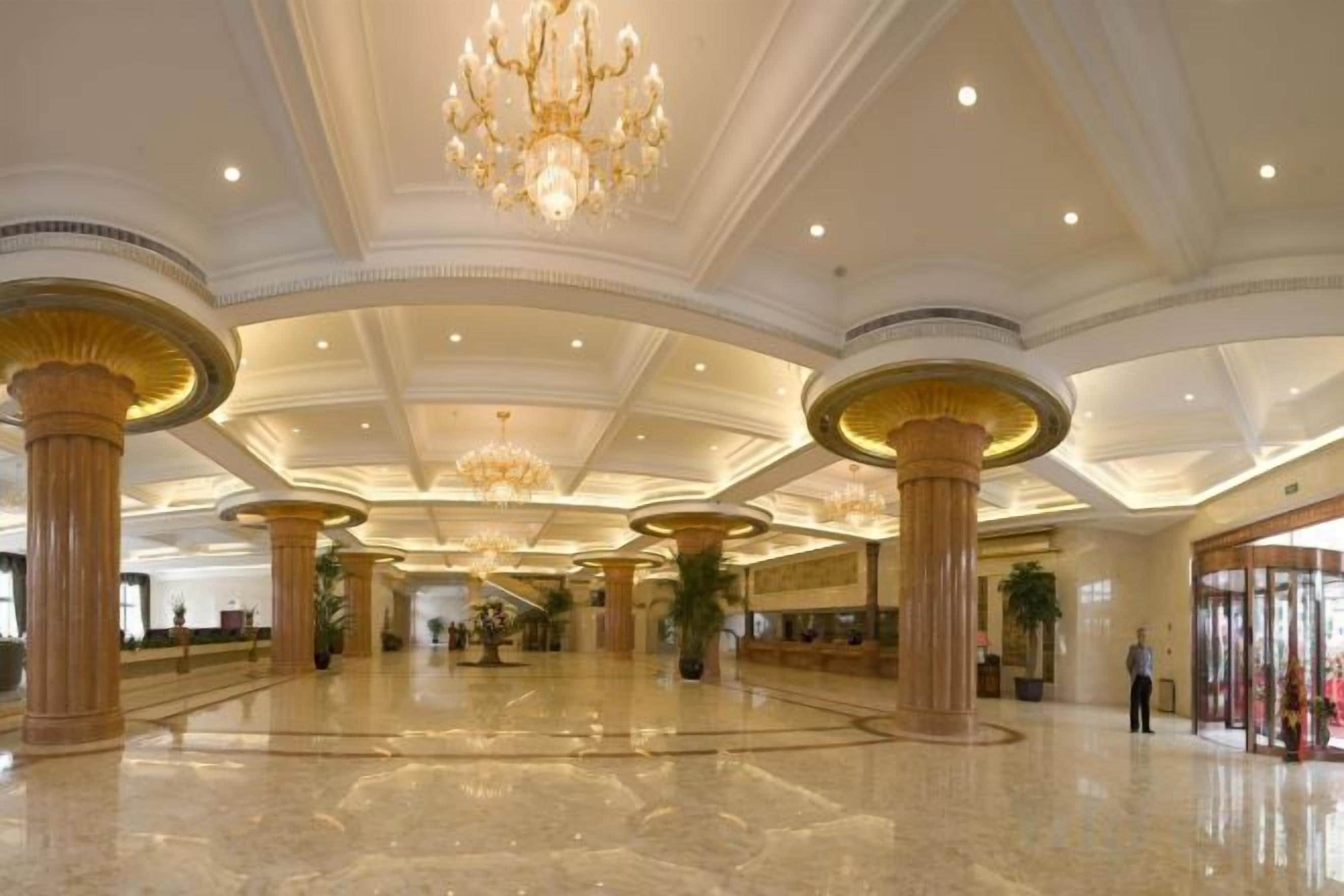 Un vestíbulo amplio con techos altos, grandes columnas y candelabros.