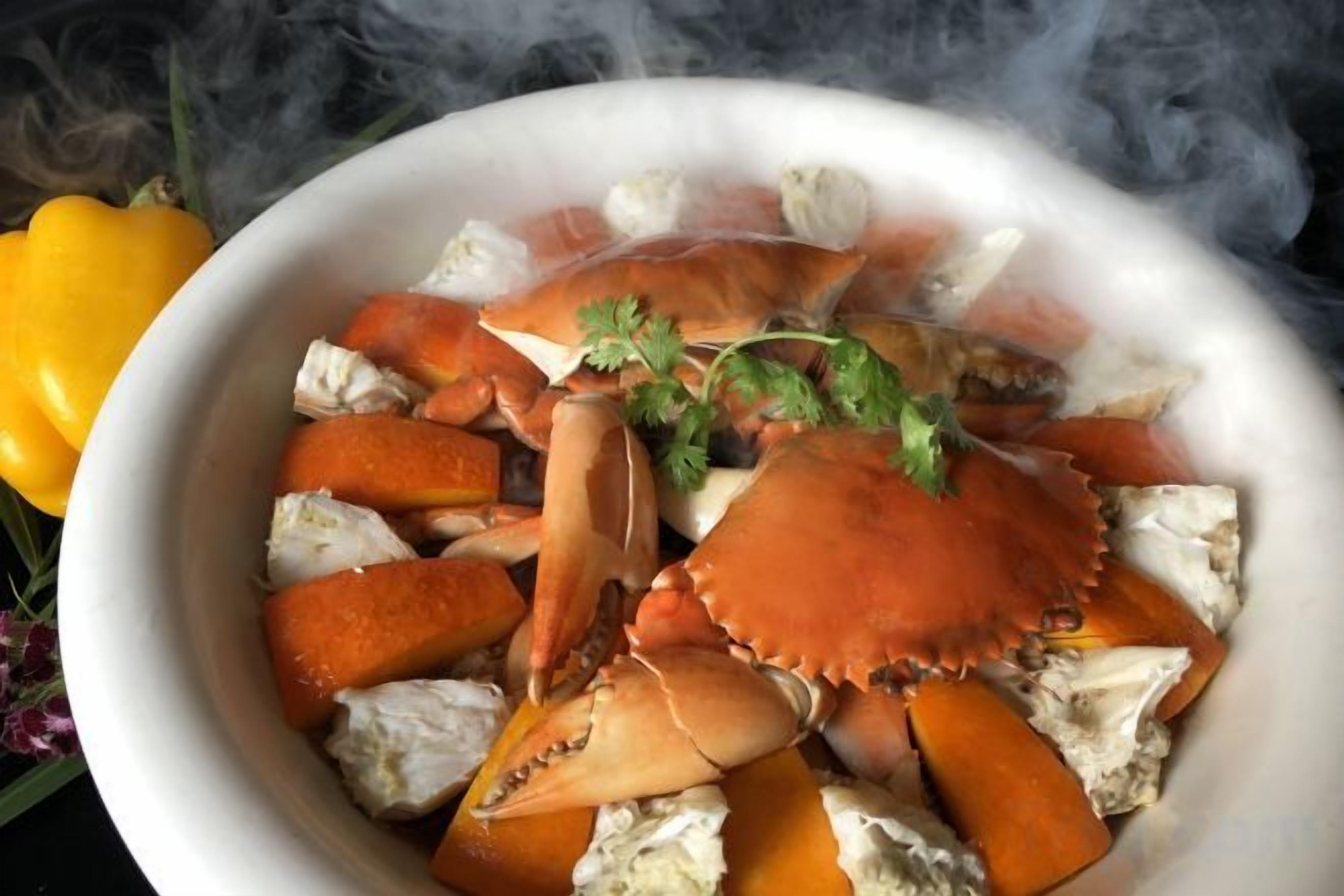 A bowl of crab with a garnish, surrounded by smoke.