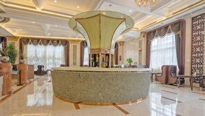 A lobby with a central round bar, a chandelier, and a large window with curtains. - Treasure Island Hotel (Wenzhou)
