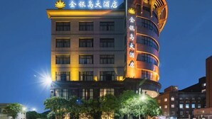 A multi-story hotel with a prominent curved facade, illuminated signage, and a series of windows. - Treasure Island Hotel (Wenzhou)