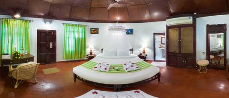 A circular bed with a canopy, a wooden ceiling, and a tiled floor.