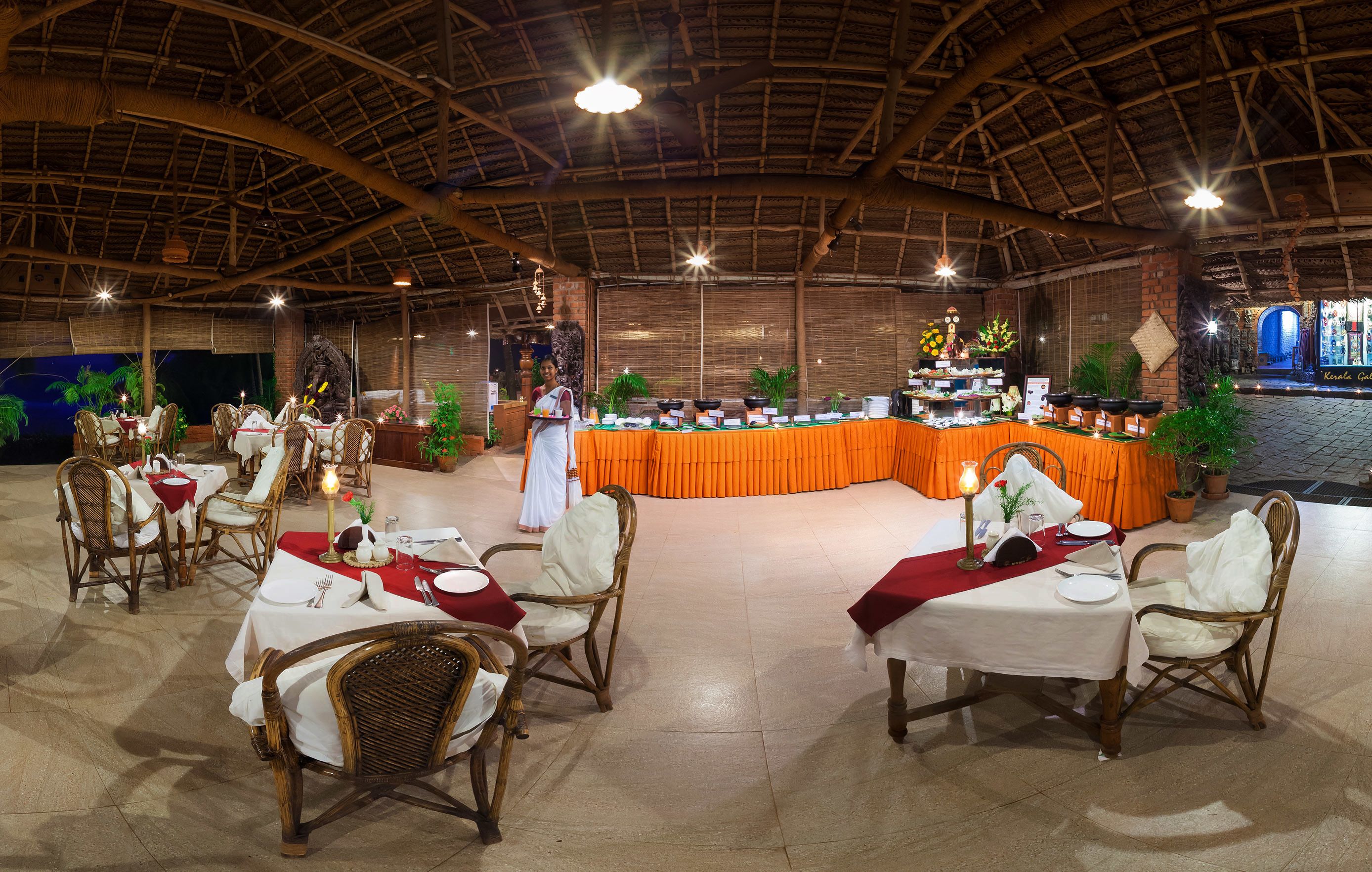 A restaurant with round tables, wicker chairs, and a buffet area.