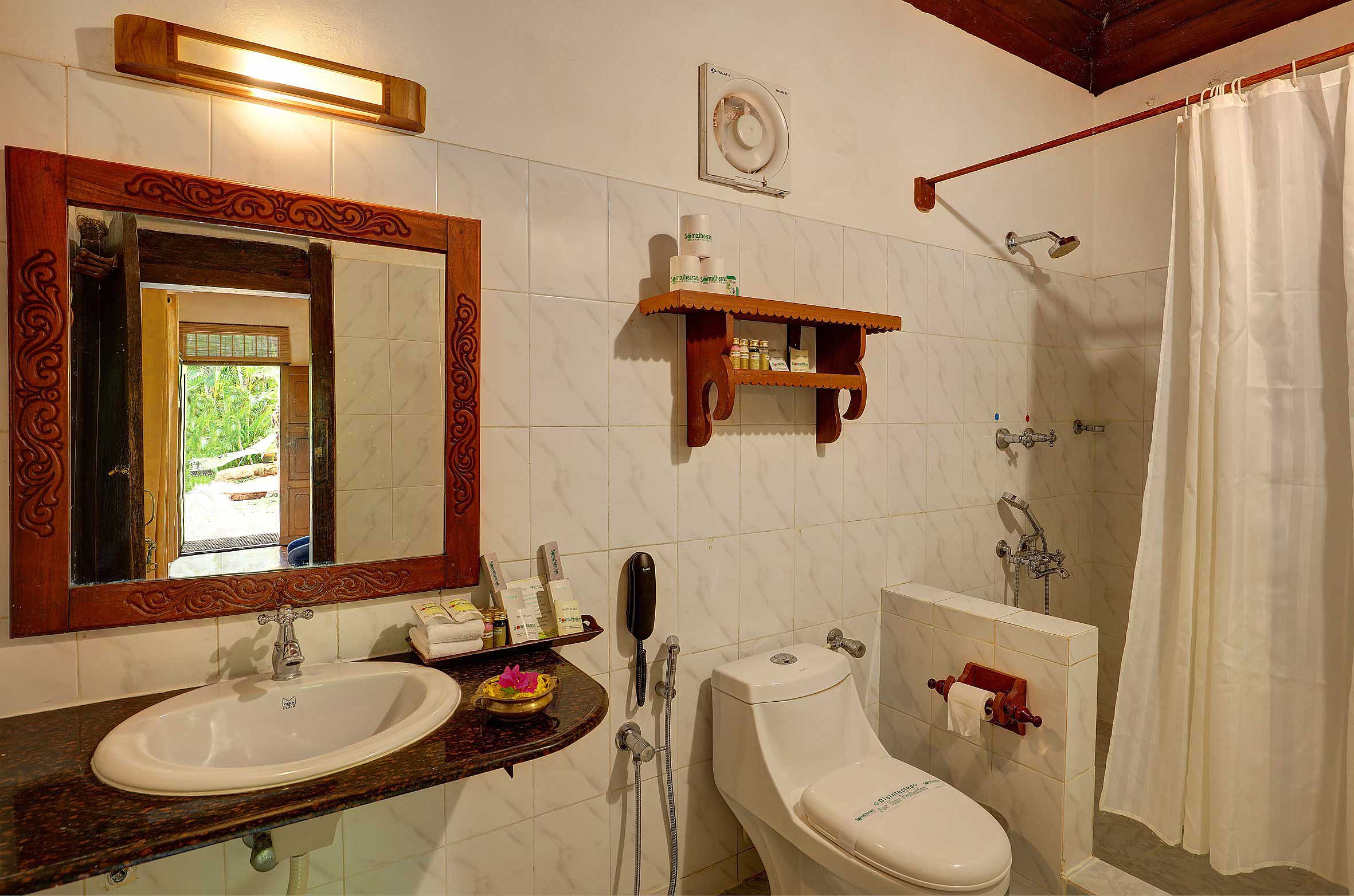 A bathroom with a sink, mirror, toilet, shower, and a towel rack.