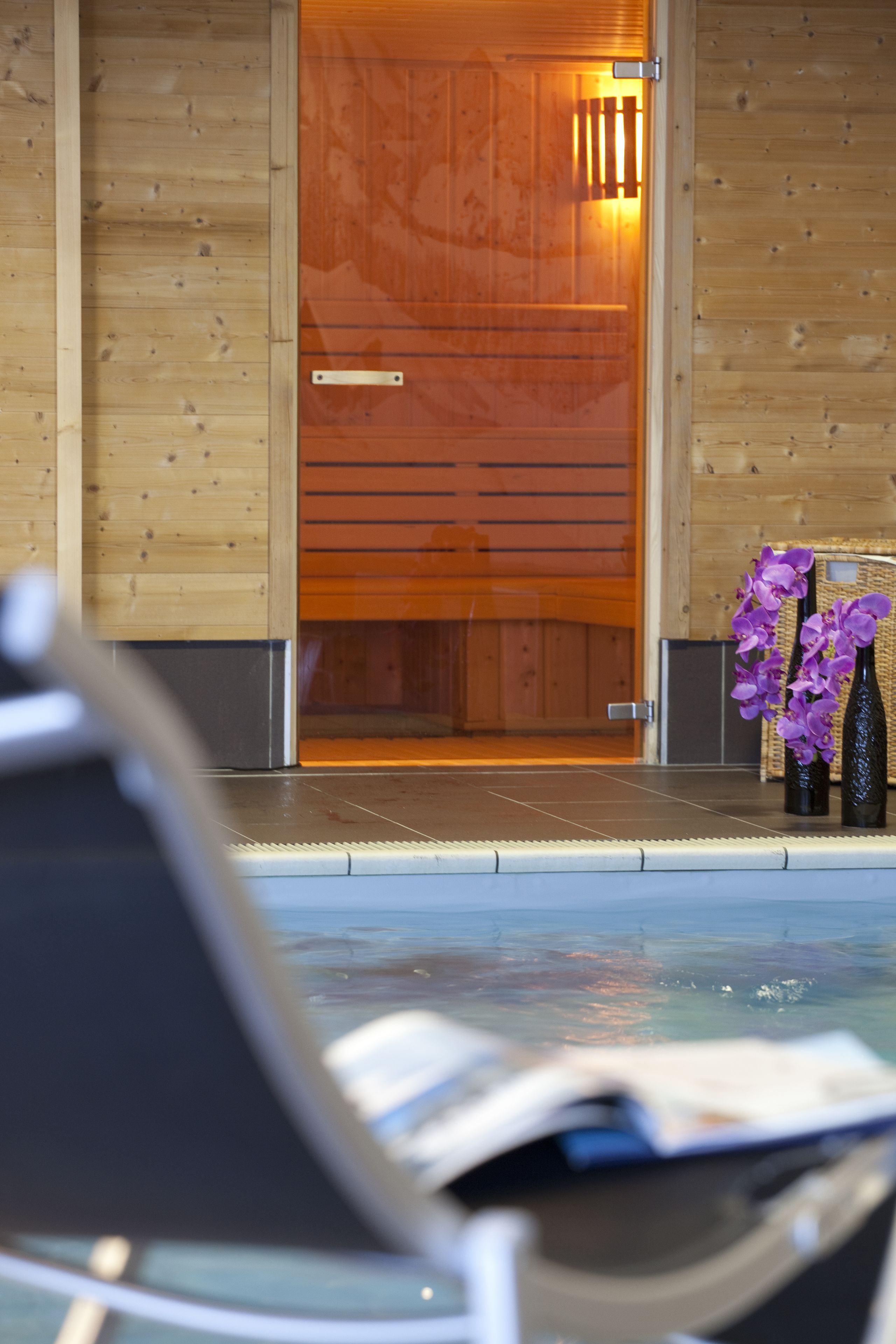 A wooden cabin with a pool, a door, and two purple flower vases.
