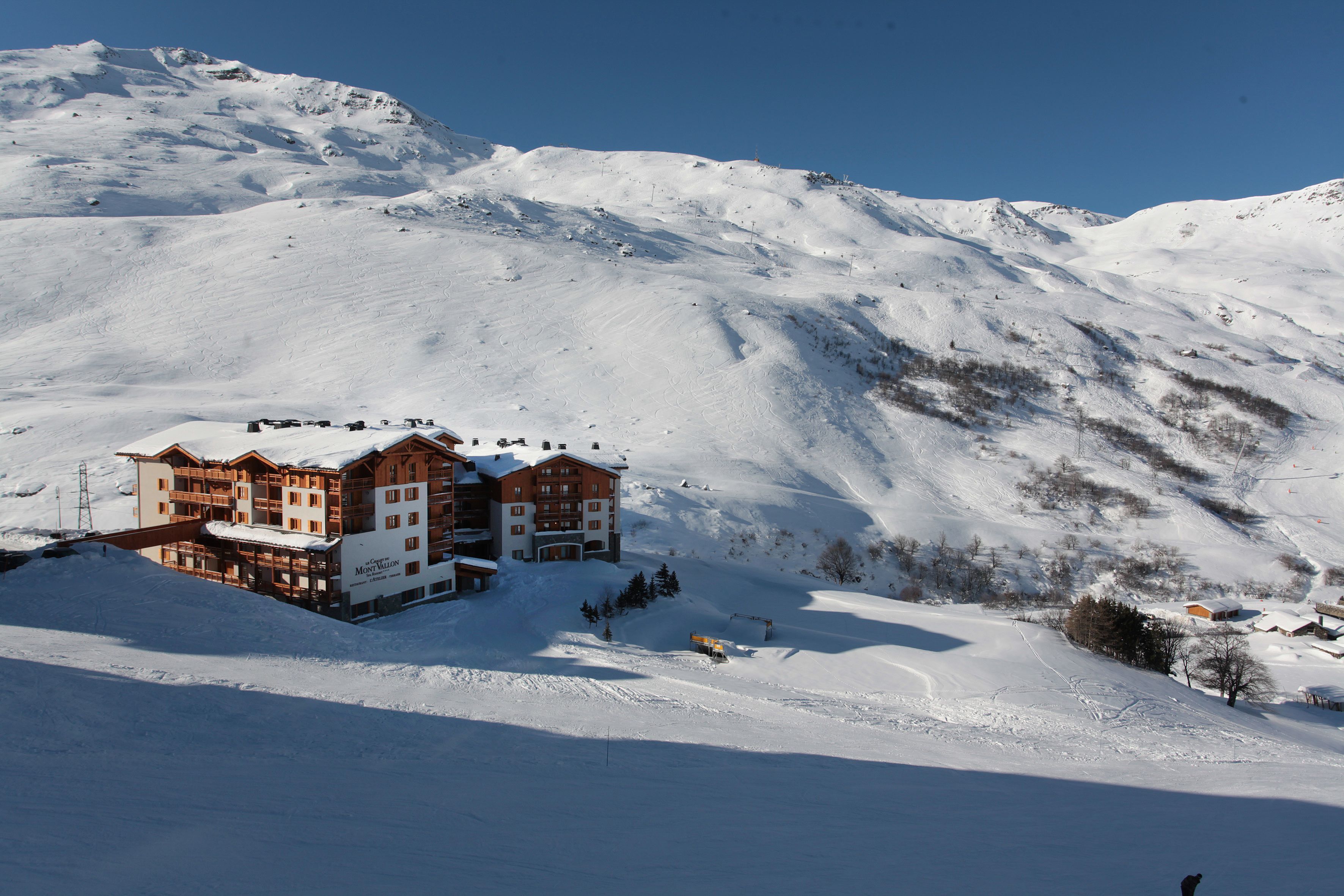 A large, multi-story hotel with a ski slope in the background.