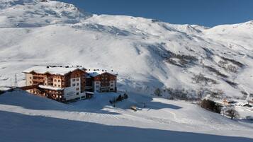 A large, multi-story hotel with a ski slope in the background.