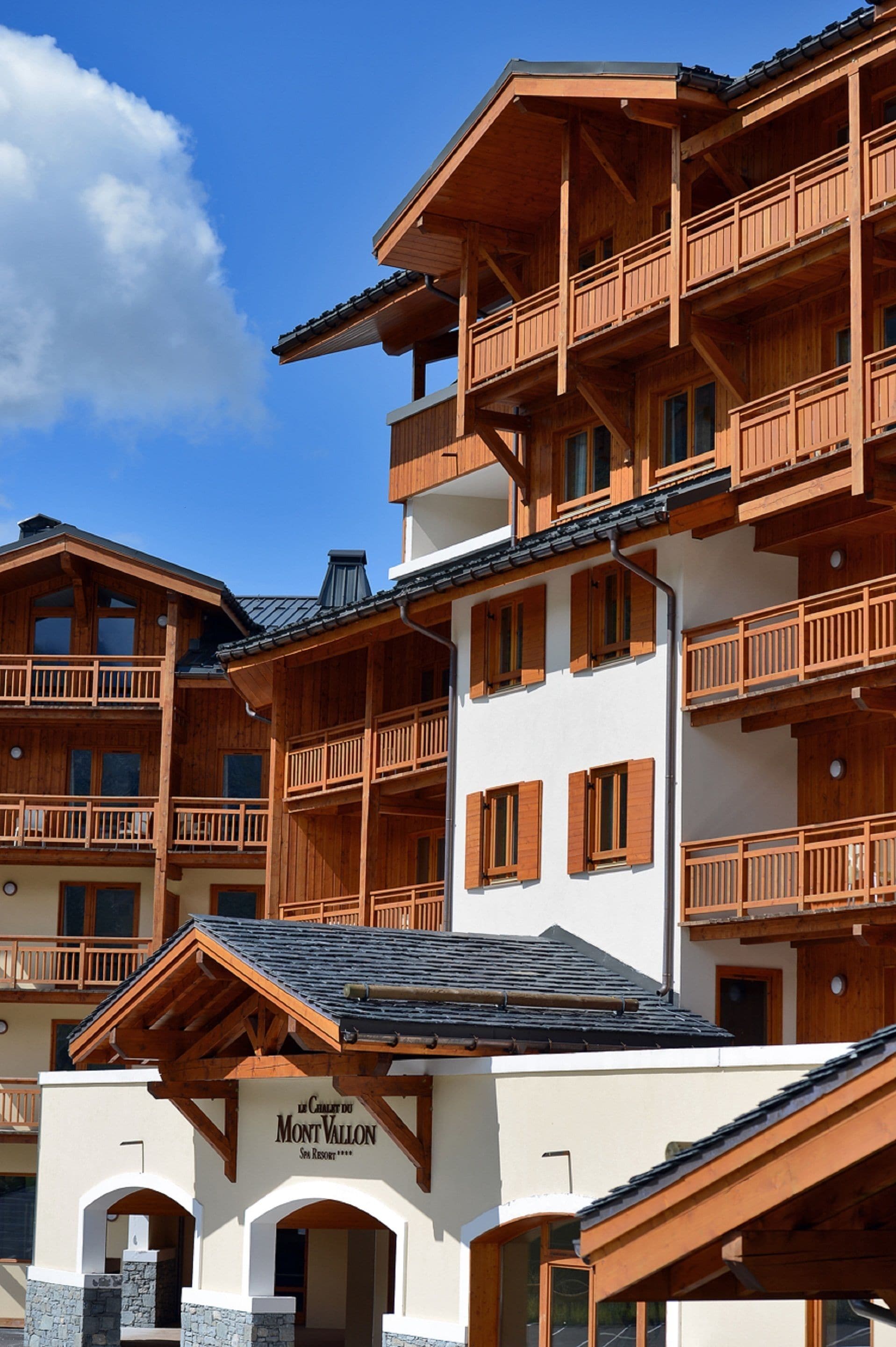 Un edificio de madera de varios pisos con balcones, una entrada de piedra y un letrero que dice 'Mont Vallon'.