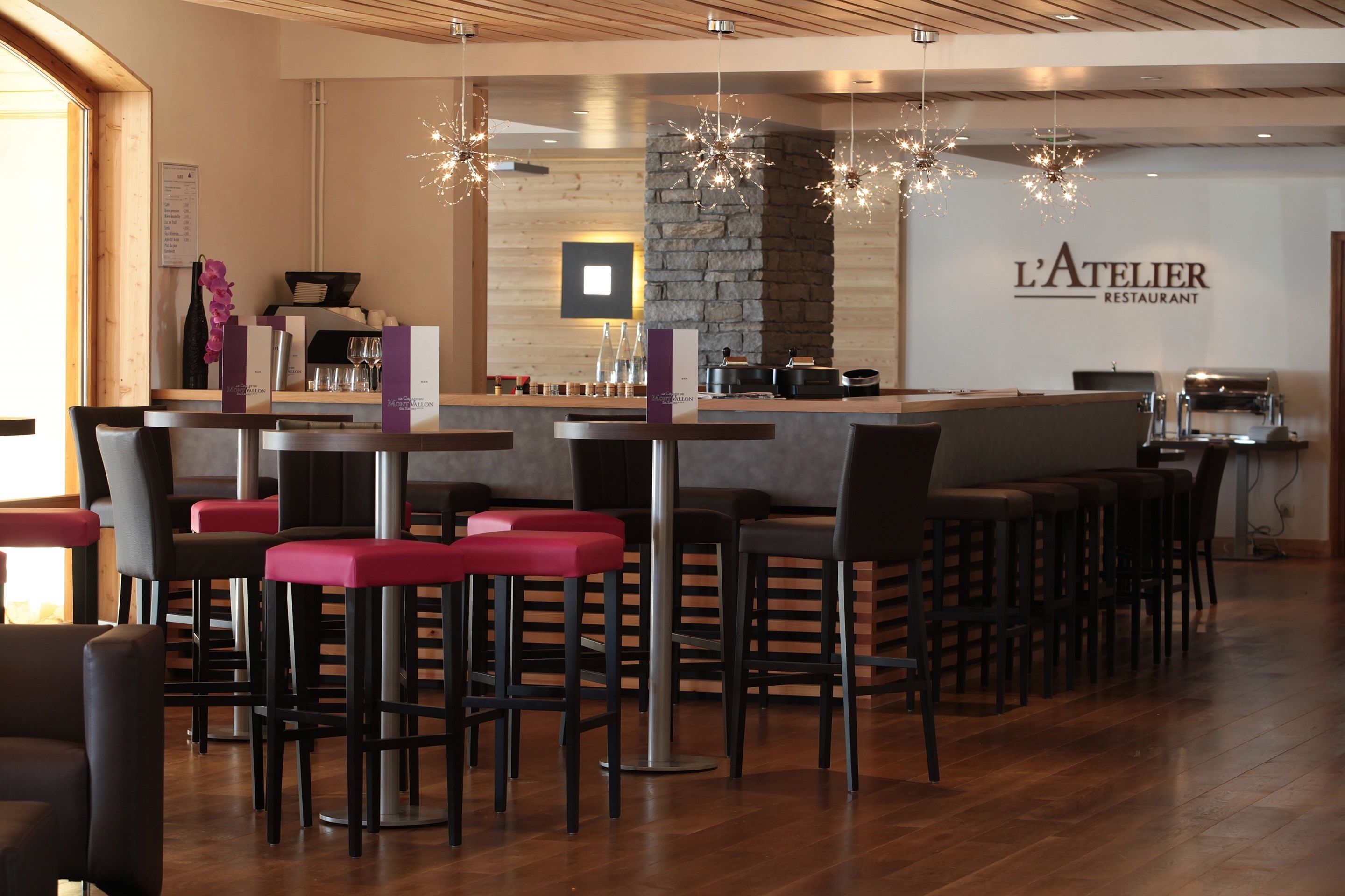 A restaurant interior with a bar area, wooden flooring, and modern lighting fixtures.