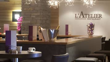 L’intérieur d’un restaurant avec un bar, des chaises hautes et un mur en pierre.