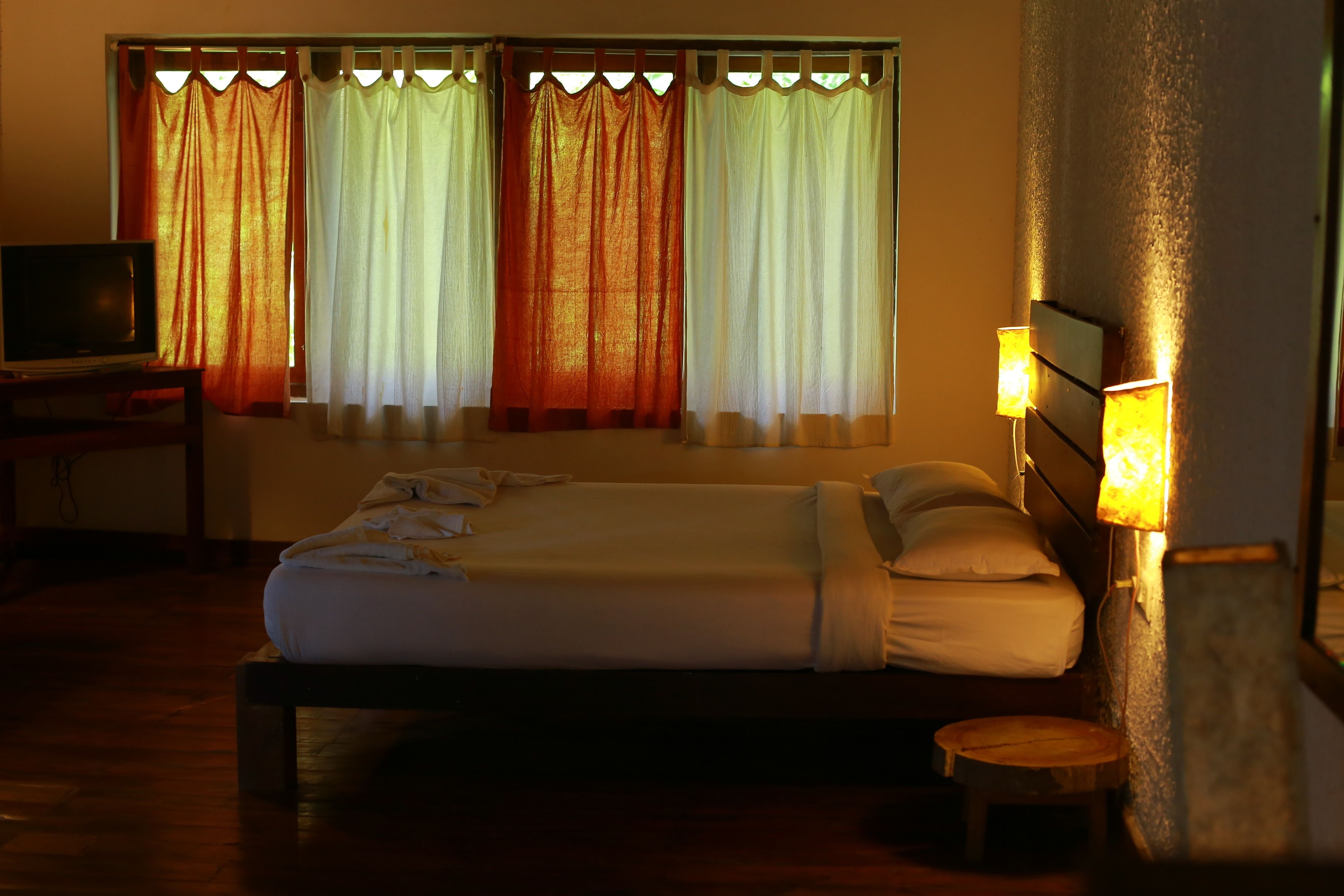 Una habitación de hotel con una cama, un escritorio con televisor y cortinas.