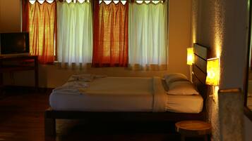 Una habitación de hotel con una cama, un escritorio con televisor y cortinas.