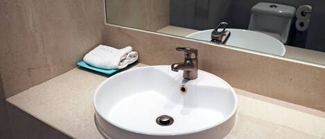 Une salle de bain avec un lavabo blanc, un miroir et une serviette posée sur le comptoir.