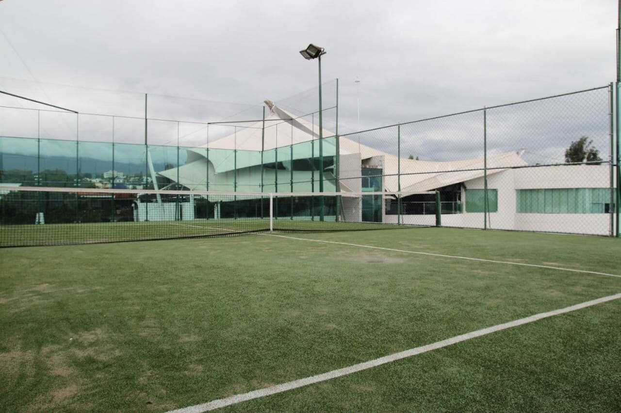 Una cancha de tenis con un edificio moderno al fondo.