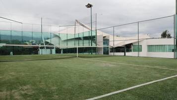 Una cancha de tenis con un edificio moderno al fondo.