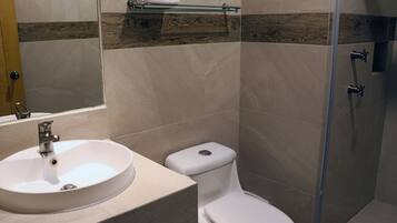 Baño con lavabo, inodoro y cabina de ducha de vidrio.