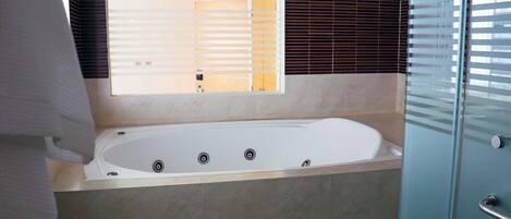 Un baño moderno con una bañera grande, un espejo y un box de ducha de vidrio.